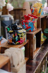Display of colorful, hand-painted ceramic containers with animal motifs on wooden shelves, creating a vibrant and artistic presentation.