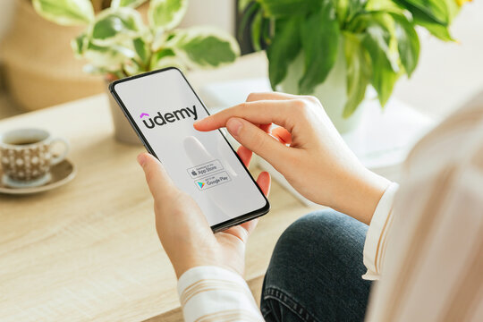Woman installing udemy app on smartphone at home