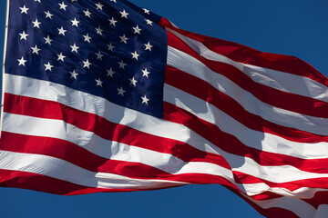 American Flag Waving In The Wind Against Deep Blue Sky.
