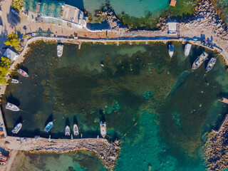 High-resolution drone image showing a small man-made harbor with several boats moored around the...