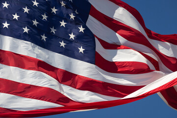 American Flag Waving In The Wind Against Deep Blue Sky.