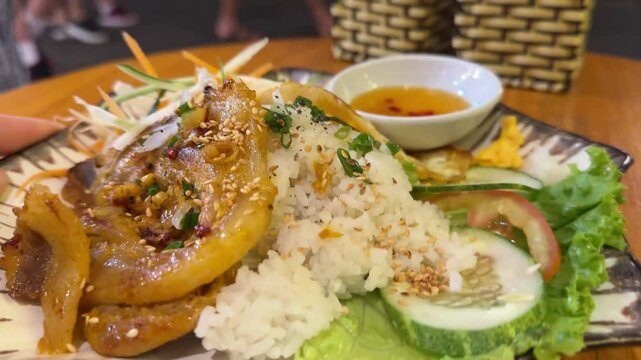 A portion of pork rice is served with very complete fillings, ranging from roast pork, red pork, eggs, ngohiang, satay and dumplings. Chinese food in white plate