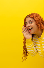Vertical image of a freckled red haired woman wearing a yellow, white striped shirt peeking out and...