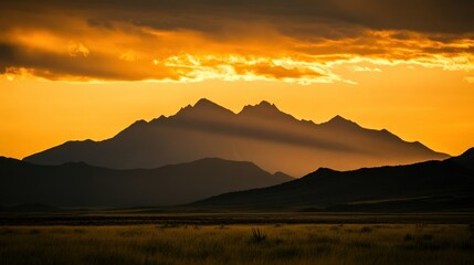 Silhouette of mountain range against golden sky at sunset or sunrise time