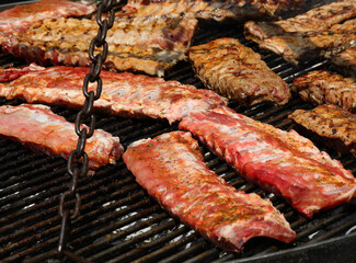 cast iron grill supported by large chains with grilled pork ribs