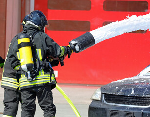 Two firefighters while spraying foamy white extinguishant on   car after   road accident