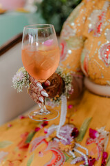 Elegant hand holds a refreshing beverage in a stemmed glass, adorned with delicate floral accents...