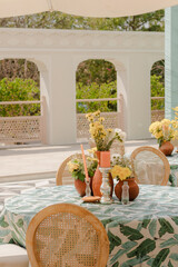 Outdoor dining table with floral arrangements, creating a serene and inviting atmosphere for a special occasion. Decorative touches enhance the overall aesthetic.