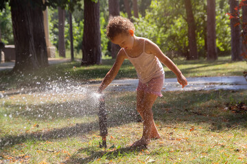 Little child playing with a garden hose on hot and sunny summer