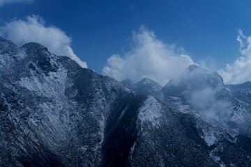 Snow covered mountains in winter with clouds and blue sky