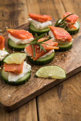 Appetizer canape. Fresh cucumber slices topped with cream cheese and smoked salmon garnished with herbs