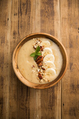 Almond butter smoothie bowl with granola in a coconut bowl, top view. Healthy vegan food concept