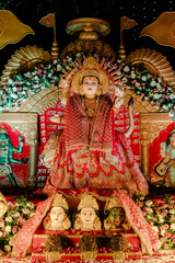 Ornate Shrine Display:  A vibrant religious display features a central deity draped in red and gold, surrounded by flowers and symbolic objects, creating a focal point.