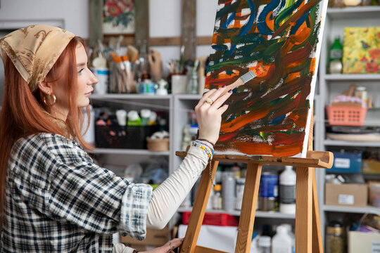 A young, innovative artist passionately painting in a vibrant and creative studio space