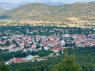 Obraz premium View from the mountain to the town of Korkuteli, Antalya. Panoramic view of the city. Houses with rooftops. Daytime