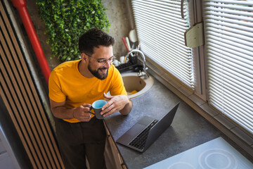relax adult man drink coffee and use laptop computer in the kitchen