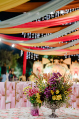 Festive floral centerpieces adorn a wedding reception, creating a vibrant and inviting ambiance...