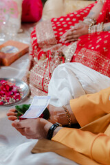 Traditional Wedding Ritual. Groom's hand holding money with bride in red sari beside. Cultural...