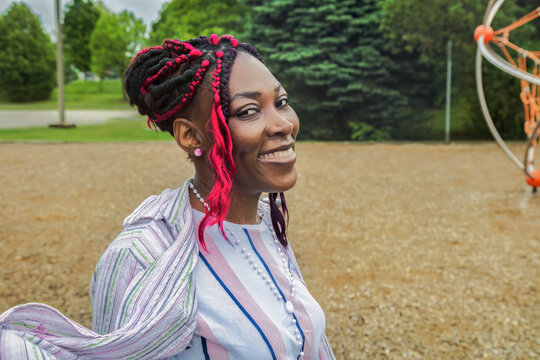Happy African American woman enjoying relaxing day walking at outdoor park playground smiling