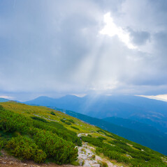 green mountain chains in dense mist and clouds under a sparkle sun