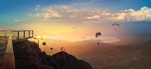 Leisure and skydiving from the Babadag mountain over the Fethiye resort, Turkey. Panoramic landscape with silhouettes of parasailing touristers flying near the top station of Oludeniz cable car. © Repina Valeriya