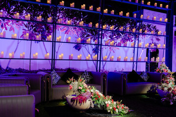 Elegant ambiance with warm candle lights, soft seating, and flower arrangements. A scene for an elegant celebration or relaxing space.