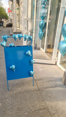 A blue display board with heart-shaped decorations in a city setting. The background features a...