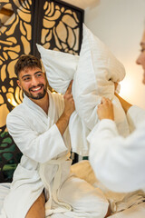 Couple in Bathrobes Having Pillow Fight