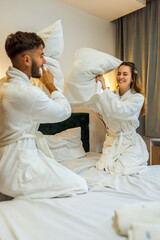 Couple in Bathrobes Having Pillow Fight