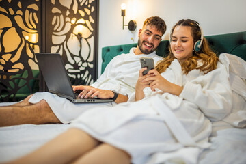 Cozy Couple in Bed Looking at Smartphone Together