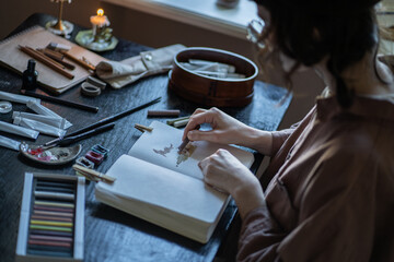 Woman illustrator drawing picture in sketch book with pastel chalks. Cartoon artist creating animation painting. Visual designer working in studio. Talented girl learning to draw at master class