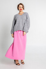 Beautiful girl of model appearance. Portrait of cheerful woman in gray jumper and pink skirt. Vertical photo. High quality photo
