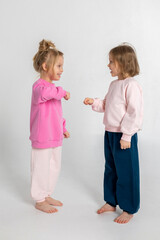 Two funny cute girls playing and having fun. Children with smiles and funny emotions on a light background. Vertical photo. High quality photo
