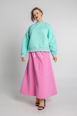 Beautiful girl of model appearance. Portrait of beautiful woman in mint color sweatshirt and pink skirt. Vertical photo. High quality photo