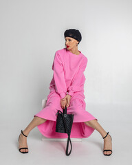 Portrait of beautiful woman in pink sweatshirt, skirt and black beret in French style on light background. Vertical photo. High quality photo