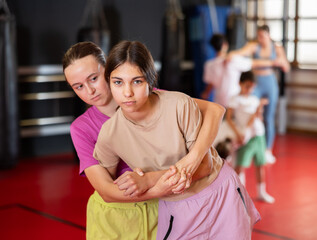 Teen girls train in pairs to strike and reflect blows of enemy. Self-defense training and Krav Maga principles, physical activity, sports self-defense classes...