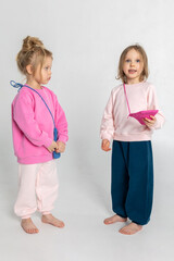 Portrait of two beautiful cute little girls. Pretty kids in colorful sweatshirt studio on light background. Vertical photo. 