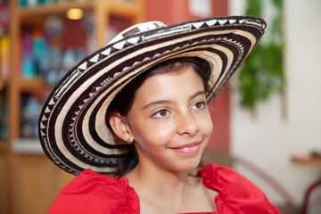Sweet teenager girl in Cartagena de Indias wearing a traditional sombrero vueltiao. Travel concept. Sitting alone. Happy girl.