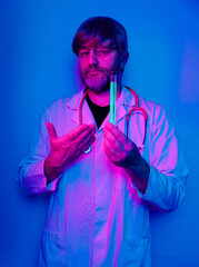 A man in a white lab coat with a stethoscope around his neck holding glass tube with blue glowing liquid medicine. Red and blue color. Doctor working in a lab on new secret drugs