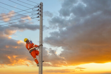 Electrician talking on a walkie-talkie working on high-voltage electricity poles, Thailand
