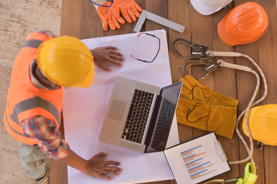 Overhead view of a construction worker standing at a table looking at his laptop, Thailand