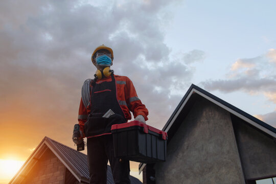 Portrait of an electrician wearing a face mask carrying a toolbox, Thailand