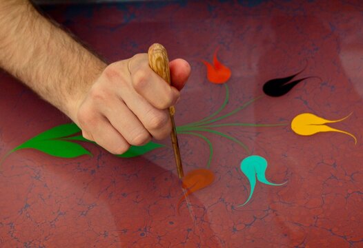 Close-up of a man creating Abstract Ebru marbling effect pattern in the shape of a tulip