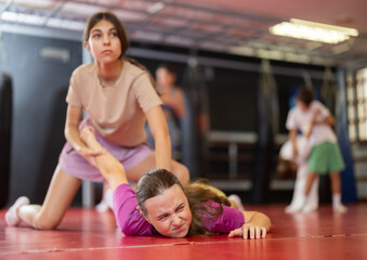 Purposeful engrossed teen girls train during self-defense fight training session and work out basic...