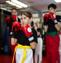 Girl in red boxing gloves at boxing and self-defense training. Portrait of a boxer girl. Group...