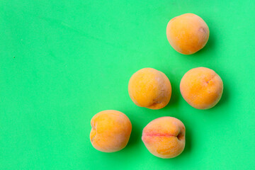 Fresh ripe apricots on green background.