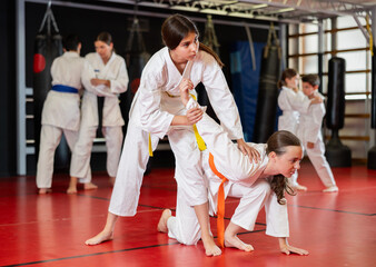 Teenage girls in white kimonos practice their technique in judo training