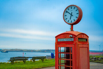 Red telephone booth over a brick wall. Old vintage english telephone booth on a cool background casting shadow.