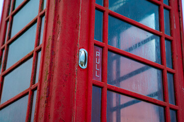 Red telephone booth over a brick wall. Old vintage english telephone booth on a cool background casting shadow.