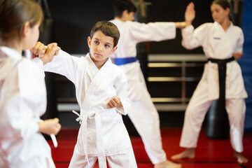 Young children boy and girl partners pupils are trained to perform defensive karate installations...